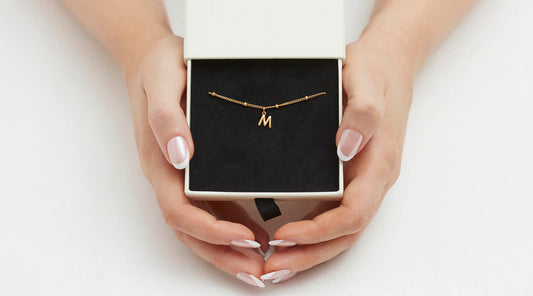 hands folding a jewellery box with a gold bracelet in it