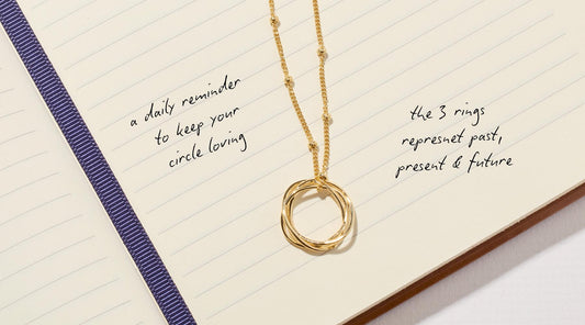 Karma necklace on a notepad with writing that explains the story behind the design