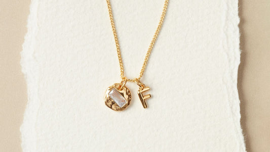 An April birthstone pendant on a gold chain with a letter F pendant