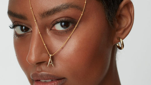 Model wearing a letter A initial necklace over her face