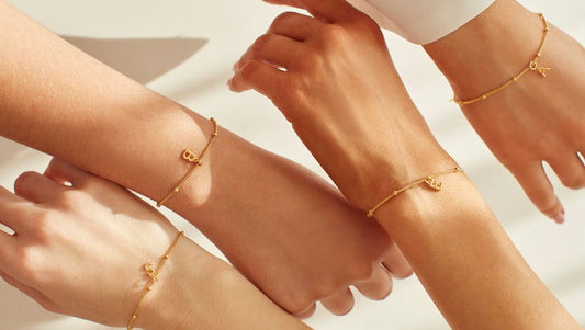 Bridesmaids arms each wearing a delicate gold initial bracelet