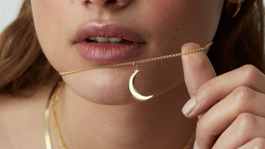 a woman wearing a gold half moon necklace